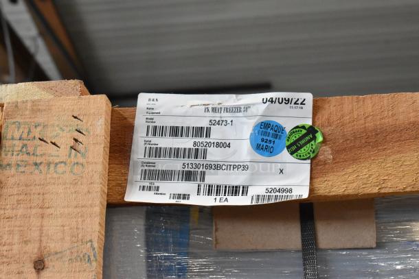 Brand new 2022 BKI 52473-1 stainless steel commercial meat freezer, on commercial casters, shown in crate with labels.