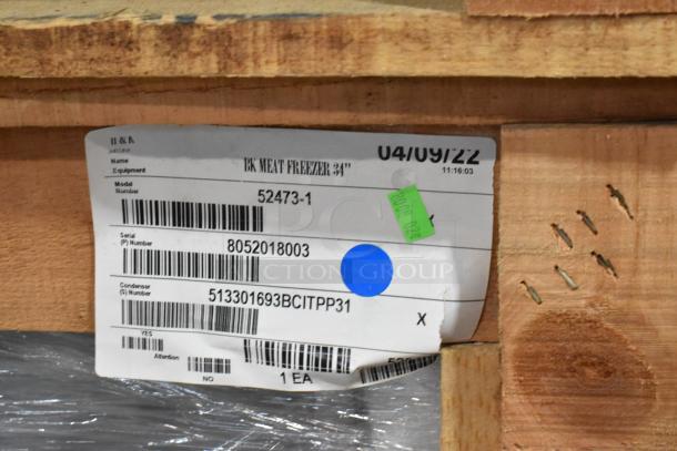 Brand new 2022 BKI 52473-1 stainless steel commercial meat freezer in crate, with tags displaying model and serial numbers.