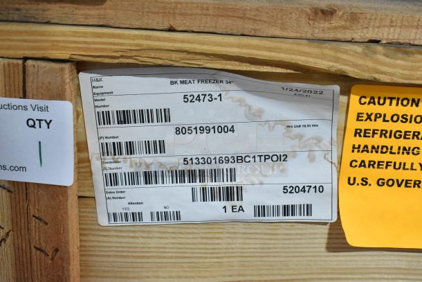 BRAND NEW 2022 BKI 52473-1 stainless steel commercial meat freezer in crate, 115 volts, 1 phase, on casters. Tags visible.