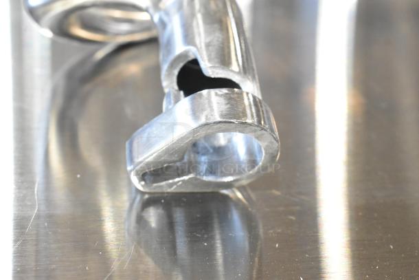Close-up of a metallic dough hook, part of a brand new scratch and dent auction set including a paddle.