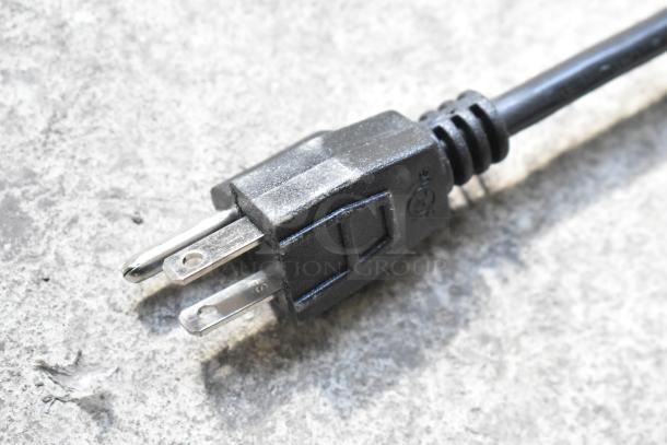 Close-up of a black electrical plug from the ServIt 423HSW2024 heated shelf warmer, featuring three prongs.