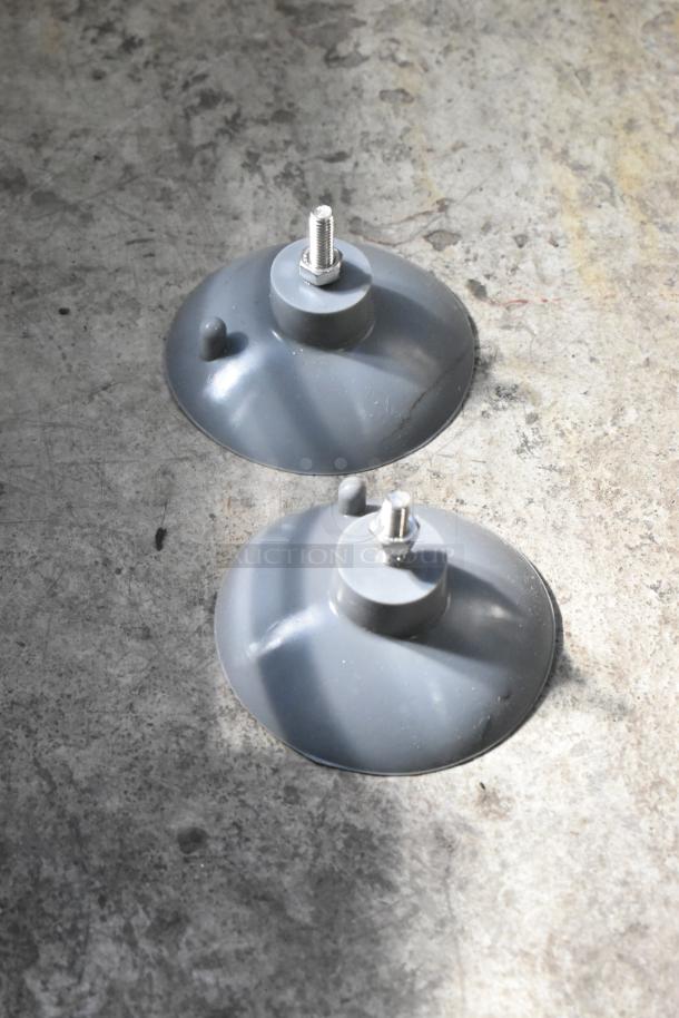Two gray suction cups for Garde 181FC38 Heavy-Duty French Fry Cutter on concrete floor, used for stability and mounting.