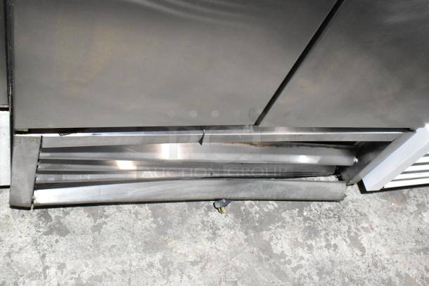 True T-35 stainless steel commercial 2-door reach-in cooler, visible lower section with minor denting. Includes poly-coated racks.