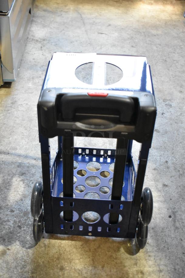 Metal dolly with blue finish, four wheels, perforated design. Features a red handle latch. Excellent condition for heavy-duty use.