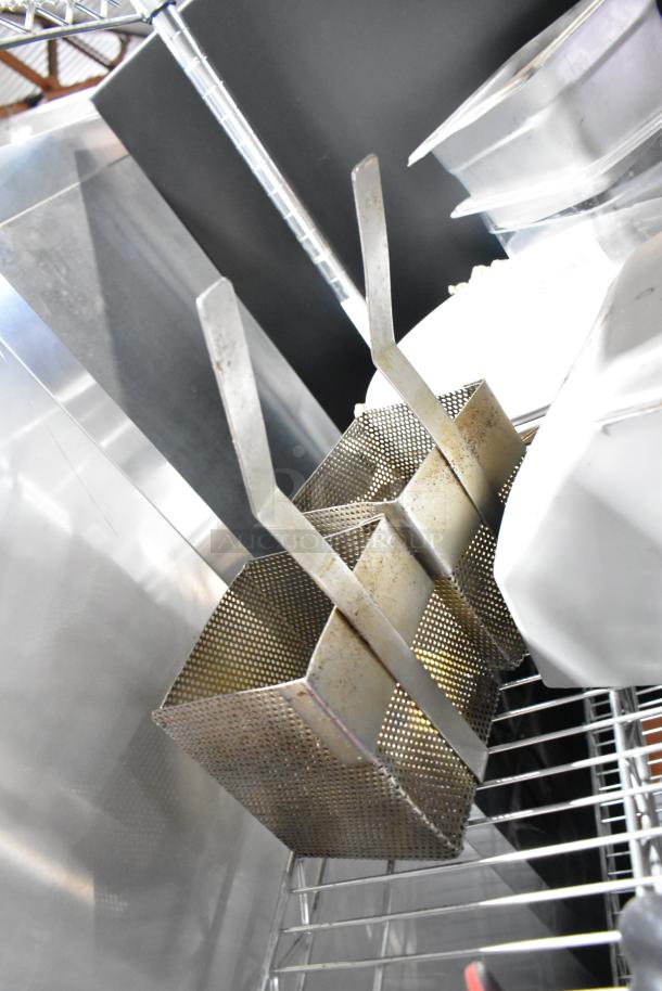 Tiered lot of kitchen items including metal baskets on a wire rack. Items show signs of wear. No visible labels or tags.