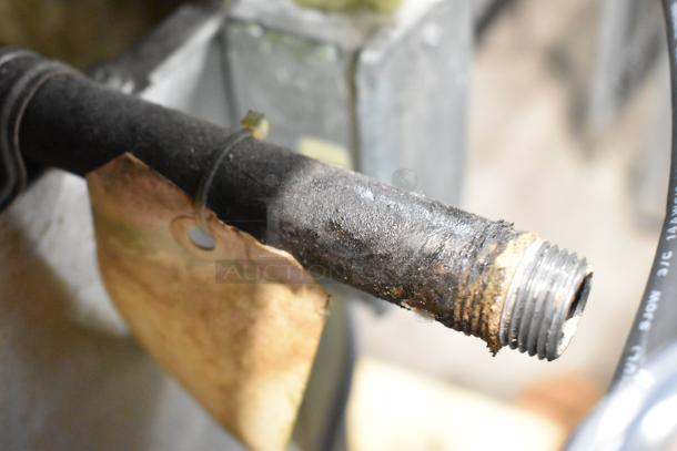 Avalon ADF24G-BA fryer's worn gas connector pipe with an attached tag, showing signs of rust and wear.