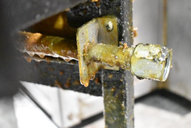 Close-up of a Henny Penny 600 fryer component with signs of use, showing grease buildup and wear on the metal part.