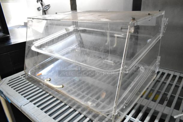 Clear poly countertop dry merchandiser case with dual shelves, transparent design, visible wear, ideal for displaying goods.