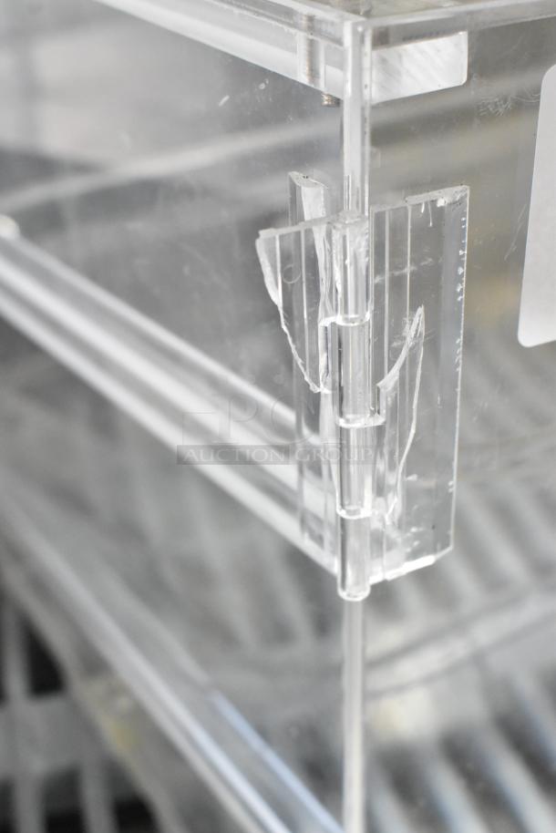 Clear poly countertop dry merchandiser case with visible hinge and light wear. Suitable for displaying goods.