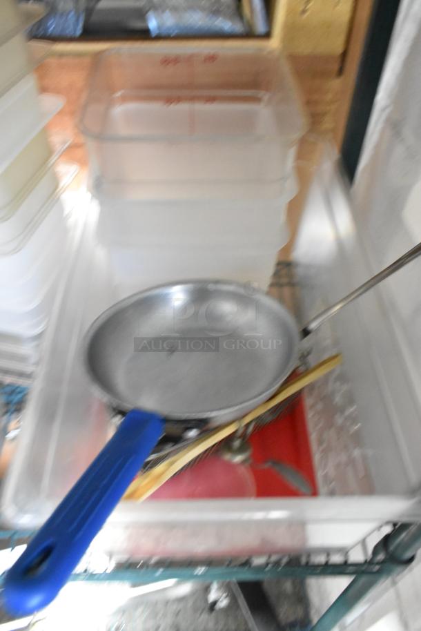 Two-tier lot of poly bins, cutting boards, and fry baskets on auction. Includes stainless skillet with blue handle.