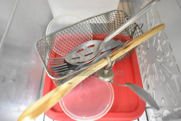 Two-tier lot with metal fry basket, slotted spoons, red poly bin, and cutting board. Assorted kitchen items in mixed condition.