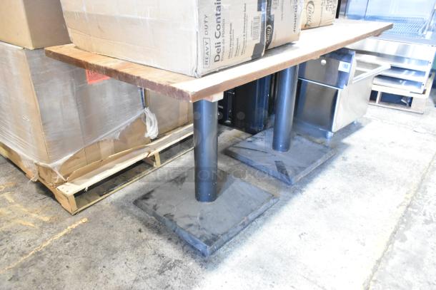 Wooden table on two sturdy black metal bases, showing wear; used condition. Suitable for dining or workspace.