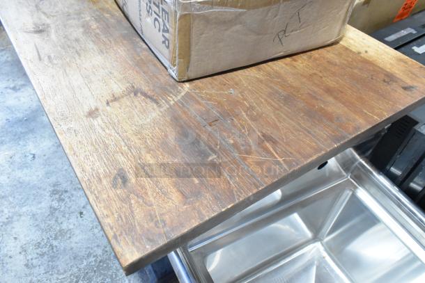 Wooden table with aged surface on two black metal table bases. Visible wear adds character.