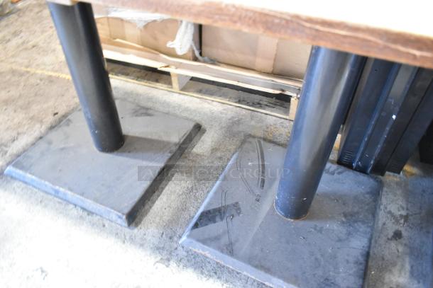 Wooden table on two sturdy black metal bases, slight surface wear, suitable for dining or office use.