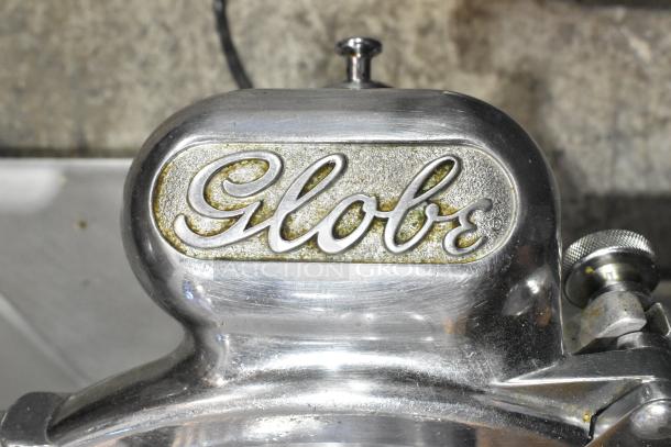 Globe 660 Metal Commercial Meat Slicer with Blade Sharpener. Features durable design and "Globe" logo. 115 Volts, 1 Phase.