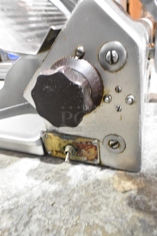 Globe 660 metal commercial meat slicer with blade sharpener, 115 volts, scratches on surface, visible rust near control knob.