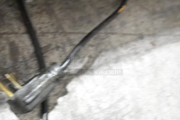 Blurry image of an electrical plug on a textured surface, possibly related to an Autofry MTI-5 fryer.