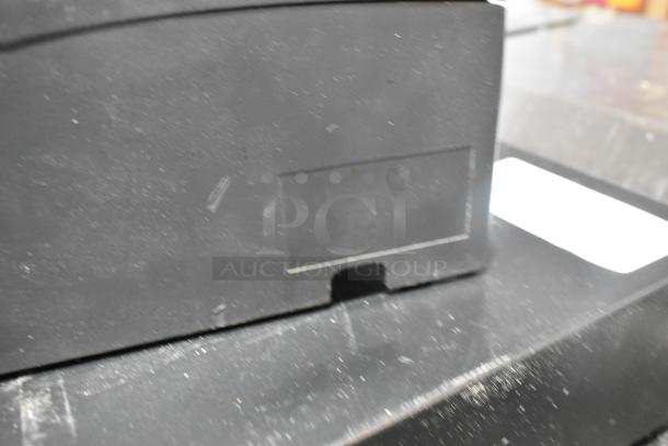 Cecilware model 721350 showing part of the black metal cash drawer, with a partial view of Epson receipt printers in the background.