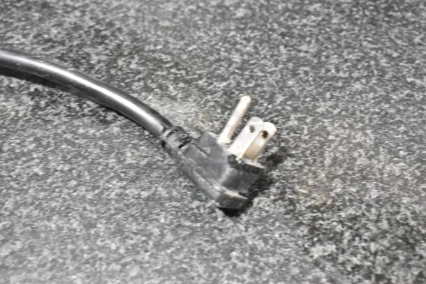 Close-up of a black electrical plug on a black stone pattern surface, part of the Atosa P-93-GR pizza prep table.