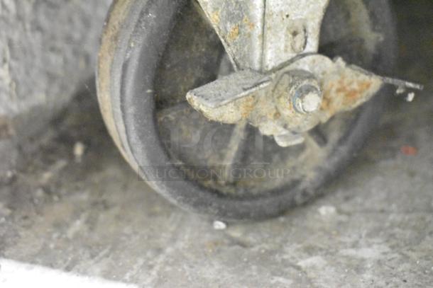 Close-up of a commercial caster from a 2020 Padela PDS-48-HC stainless steel prep table, showing signs of wear.