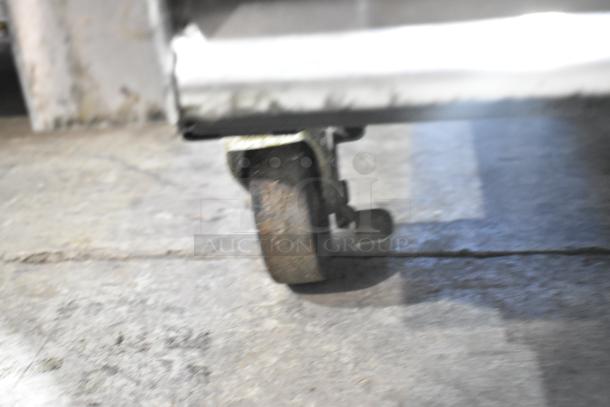 Rusty caster wheel of a 2016 True T-49 stainless steel commercial cooler, indicative of floor mobility.