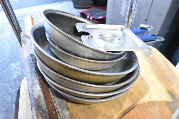 3-tier lot of kitchen items including wooden pizza peels, stainless steel drop-in bins, skillets, and round baking pans.