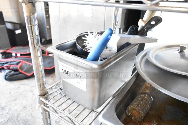 3-tier lot with wooden pizza peels, stainless steel bins containing utensils, skillets, and round baking pans. Label reads "156 QTY Tier Lot".