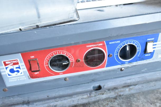 Metro C5 metal commercial heated holding cabinet controls with temperature and moisture settings, on/off switch visible.
