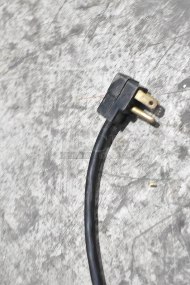 Power cord of the Beverage Air BB72HC-1-GS-B-27 cooler, showing three-prong plug detail, on textured surface.