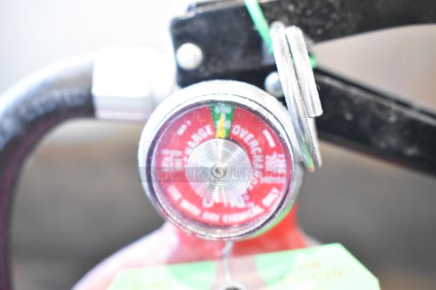 Close-up of a Kidde fire extinguisher gauge showing needle in the green, indicating normal pressure.