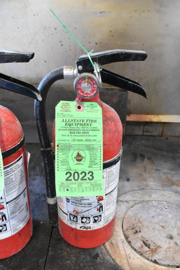 Two Kidde fire extinguishers with Allstate Fire Equipment inspection tags dated 2023. Visible instructions and condition indicative of use.
