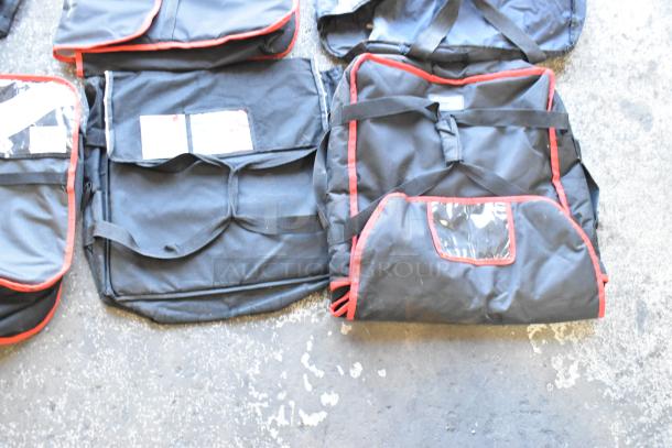 Seven black hot food carrying bags with red trim on concrete floor, used condition, clear ID pockets.
