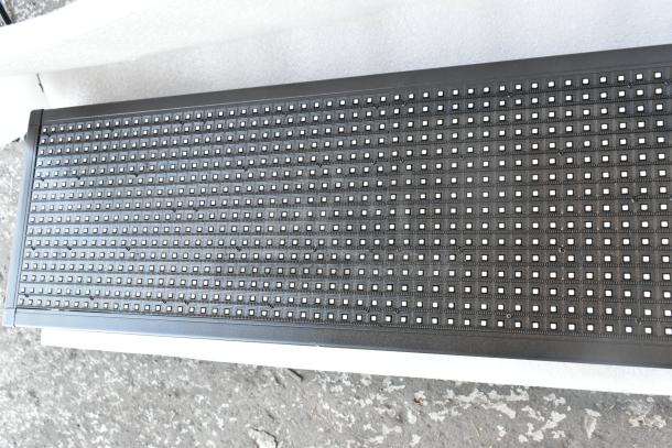 LED display panel in original box, black frame, grid of LEDs, unused condition, ideal for advertising or events.