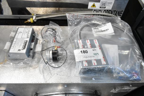 Four brand new scratch and dent items, including Fenwal Controls automatic ignition system and Delfield Assy 000-282-00HE-S, labeled with quantity tag.