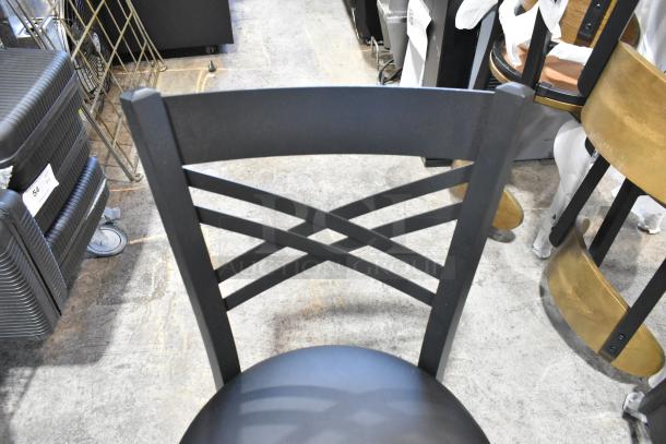 4 new Lancaster black metal cross back dining chairs with black seat cushions, minor scratches and dents visible.