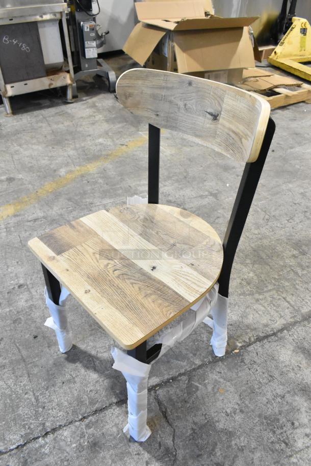 Brand new Lancaster Table & Seating black metal chair, wooden back and seat, dining height, protective wrap on legs.