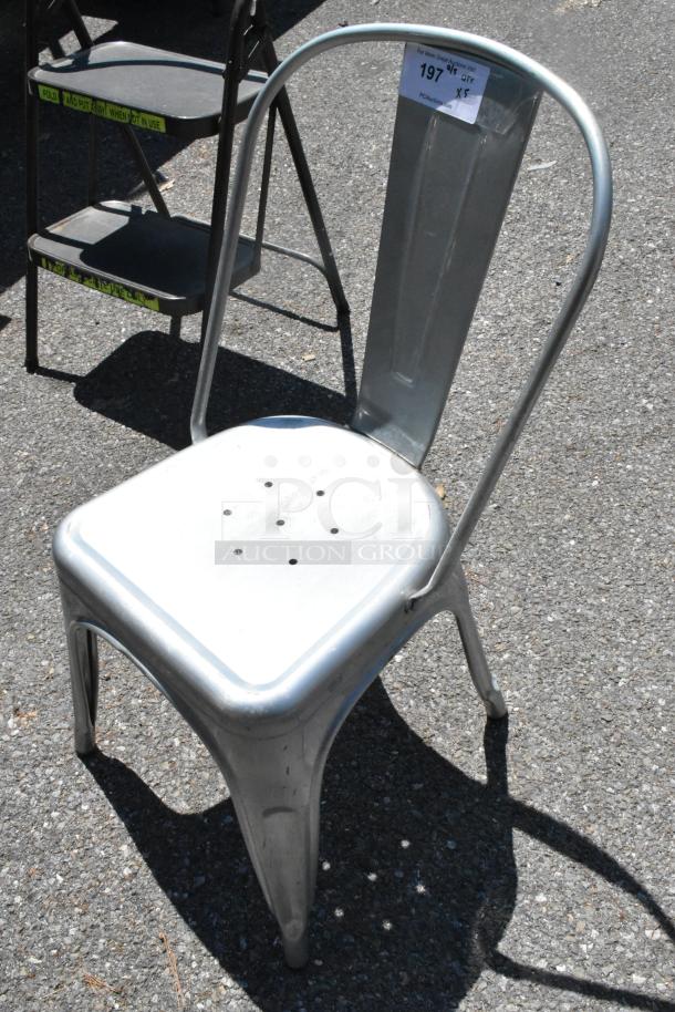 Metal Tolix style dining chair in silver, stackable, with backrest. Auction lot includes five chairs. Good condition.