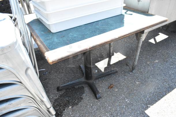Green table with wood pattern edge on black metal base, fair condition. Ideal for versatile use.