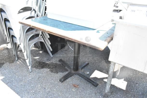 Green table with wood pattern edge, black metal base. Condition appears used. Suitable for indoor or outdoor use.