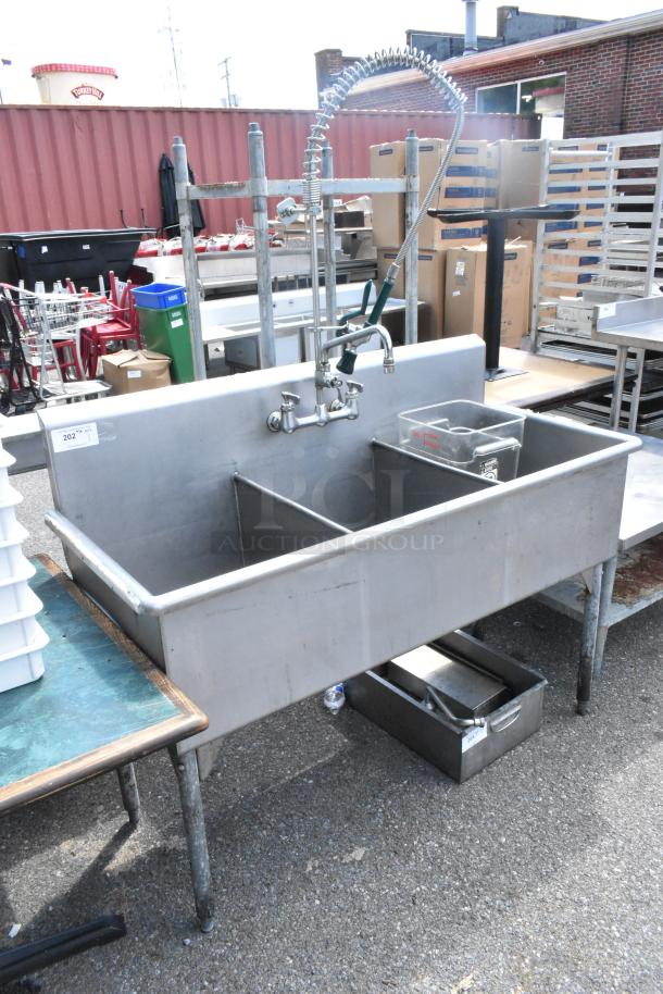 Stainless steel 3-bay sink with faucet, handles, and spray nozzle attachment. Slightly worn condition.