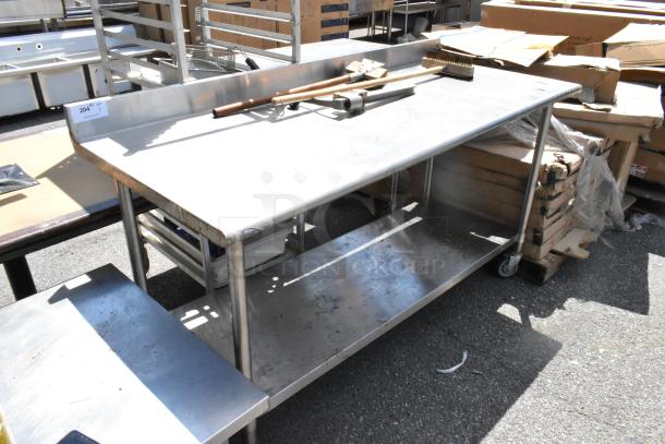 Stainless steel table with two grill brushes, can opener, and metal under shelf on commercial casters; used condition.