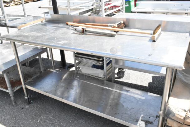 Stainless steel table with two grill brushes, can opener, metal under shelf, on commercial casters; used condition.