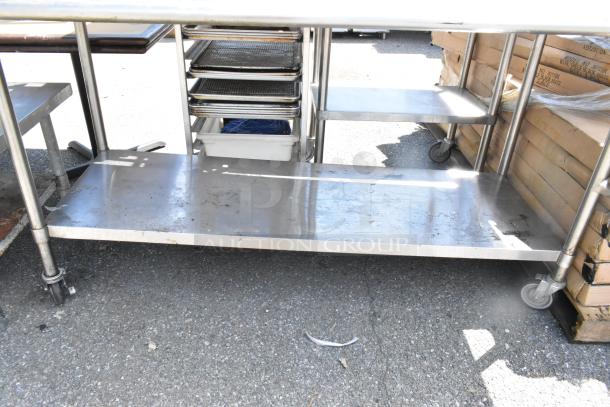 Stainless steel table on commercial casters with metal under shelf, includes 2 grill brushes and a can opener.