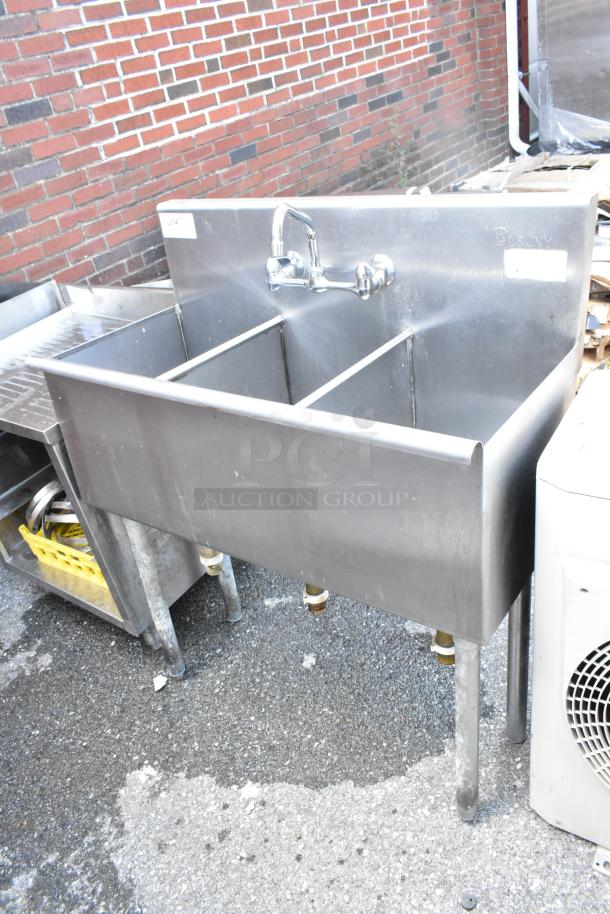 Stainless steel 3 bay sink with faucet and handles. Features three separate basins. Appears in used condition.