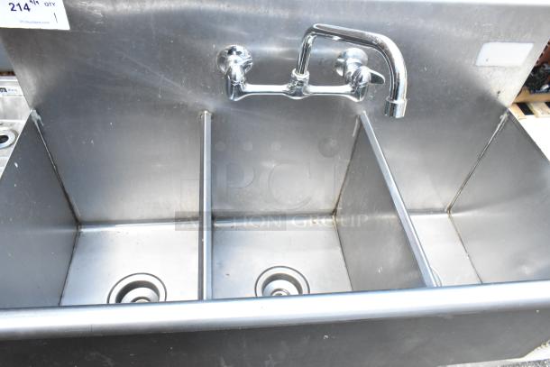 Stainless steel 3 bay sink with faucet and handles, used condition, visible auction tag on upper left.