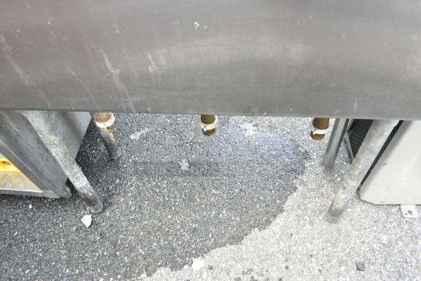 Stainless steel 3 bay sink with faucet and handles, showing plumbing connections underneath. Slight wear visible.