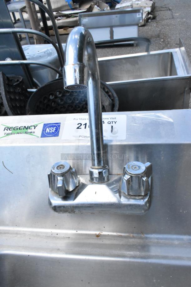 Regency stainless steel single bay wall mount sink with faucet and dual handles. NSF certified. Slight surface wear visible.