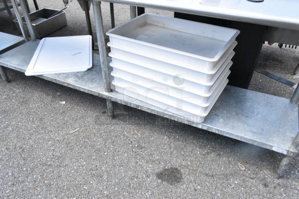 Stainless steel table with metal under shelf, holds stacked white dough bins. Good condition, ideal for bakery use.