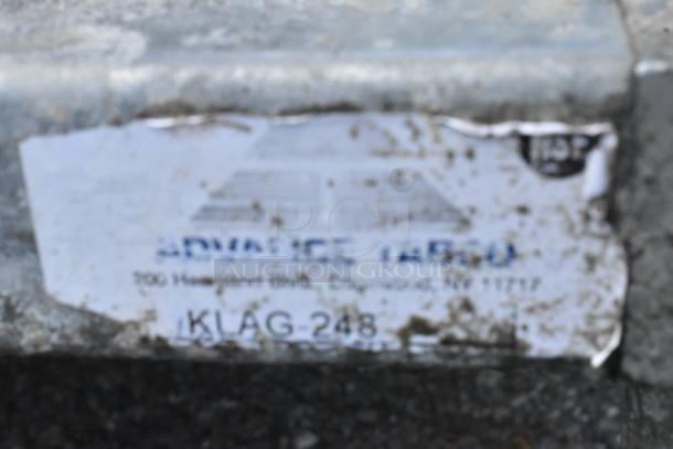 Stainless steel table with metal under-shelf and dough bins, visible wear. Label indicates "Advance Tabco," model KLAG-248.