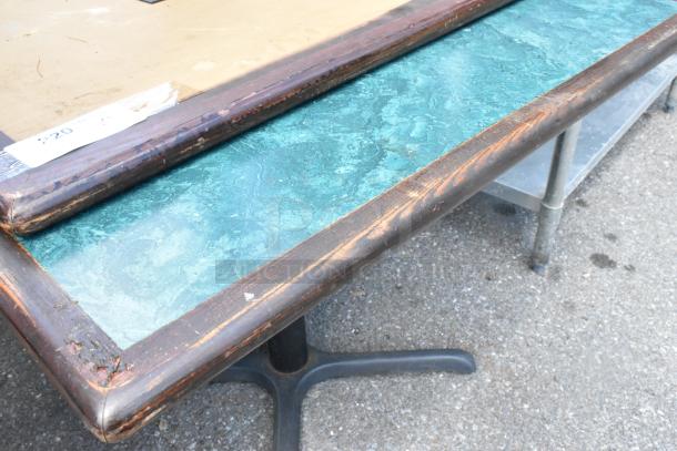Two tables with green and wood pattern tabletop, black metal base, visible wear on edges, auction lot tag attached.